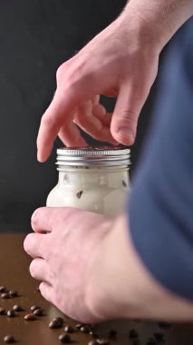 Erkekler kavanozu buzlu kahveyle kaplar ve metal bir kokteyl çubuğu koyar..