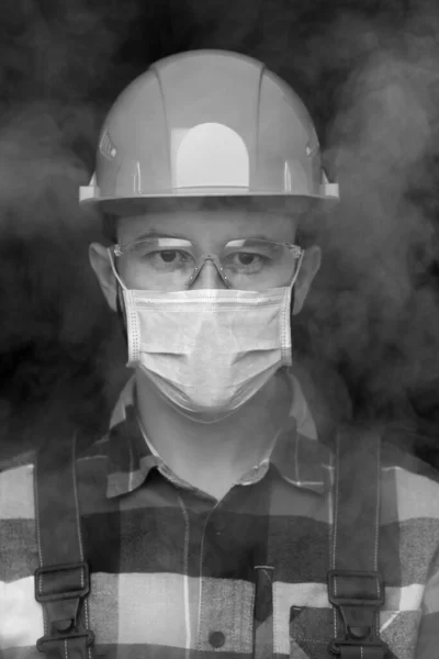 헬멧,마스크, 안전 안경을 쓰고 연기 속에서 작업하는 사람의 흑백 초상화. — 스톡 사진