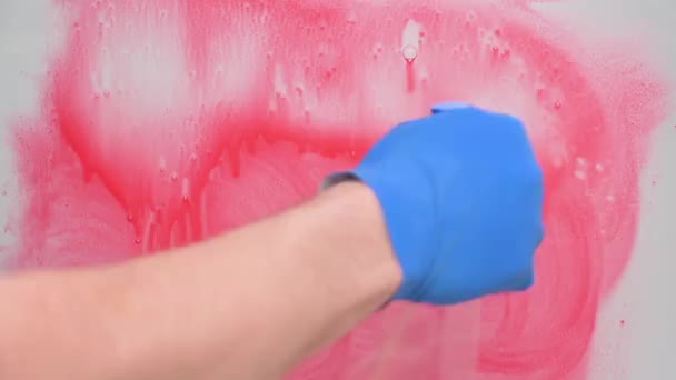 コロナウイルスの概念を停止します。青いゴム手袋の手は赤い塗料からガラスを洗浄します — ストック動画