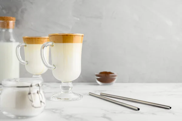 Korean Dalgona coffee in tall glass mug. Trendy krim penyegaran dicambuk es kopi. Latar belakang beton abu-abu muda. — Stok Foto
