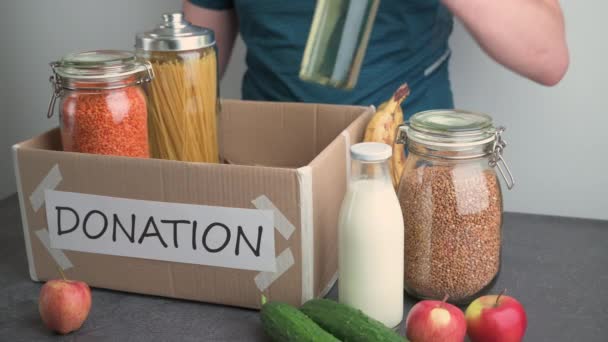 Коробка для пожертв. Дорослі кавказькі люди наповнюють картонні коробки їжею на темному столі. — стокове відео