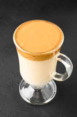 Buzlu Dalgona kahvesinin koyu arkaplandaki cam bardakta yakın çekimi. Modaya uygun kremalı kremalı kahve. Kore kahvesi..