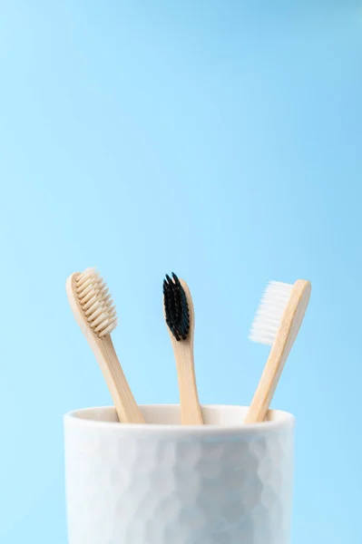 Three bamboo toothbrushes in a white glass. Zero waste and without plastic concept. — Stock Photo, Image