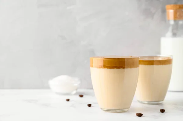 Kopi Korea. Iced Dalgona kopi dalam dua gelas cangkir di atas meja cahaya. Trendy krim penyegaran kopi dicambuk. — Stok Foto