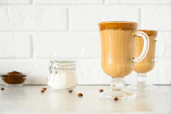 Korean Dalgona coffee in tall glass mug. Krim penyegaran Trendy dikocok kopi Macau. Latar belakang bata ringan. — Stok Foto