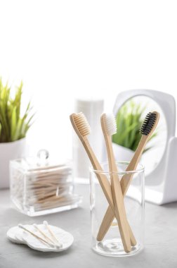 Plastik konsept yok. Çevre dostu banyo aksesuarları. Açık gri bir masada bambu diş fırçaları, pamuk yastıklar ve pamuk tomurcukları. Sıfır atık.