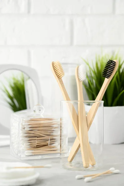 No plastic concept. Eco friendly bathroom accessories. Bamboo toothbrushes, cotton pads and cotton buds on a light gray table. Zero waste. — Stock Photo, Image