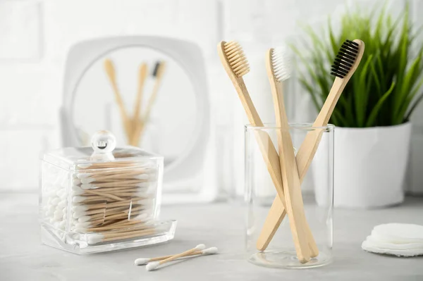 No plastic concept. Eco friendly bathroom accessories. Bamboo toothbrushes, cotton pads and cotton buds on a light gray table. Zero waste. — Stock Photo, Image
