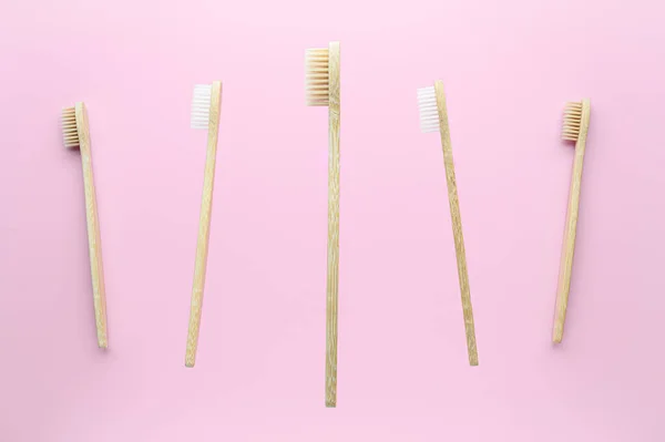 Concept de lévitation, objets volants. Les brosses à dents en bambou survolent une tasse blanche sur un fond rose pastel . — Photo