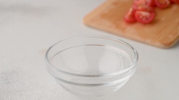 Szef kuchni wkłada pomidory wiśniowe do szklanej miski. Gotowanie letniej sałatki orzeźwiającej. — Wideo stockowe