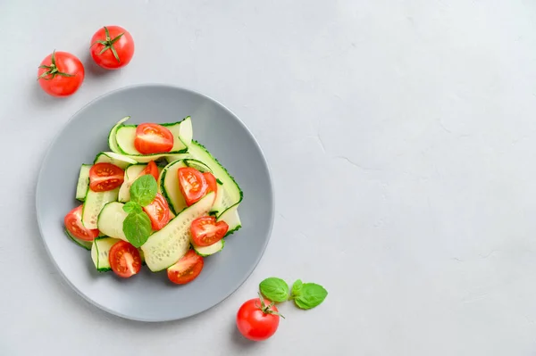 Egészséges zöldséges saláta friss cseresznyés paradicsommal, uborkával a tányéron. Vega kaja. Nyári frissítő méregtelenítő saláta. Világosszürke kőasztal. — Stock Fotó