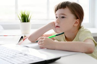 Uzaktan öğrenme çevrimiçi eğitim. Liseli kız evde ders çalışıyor, dizüstü bilgisayar kullanıyor. Kafkasyalı kız masanın yanına oturur ve okul ödevlerini yapar..