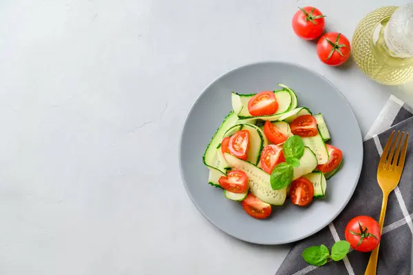 Egészséges zöldséges saláta friss cseresznyés paradicsommal, uborkával a tányéron. Vega kaja. Nyári frissítő méregtelenítő saláta. Világosszürke kőasztal. — Stock Fotó