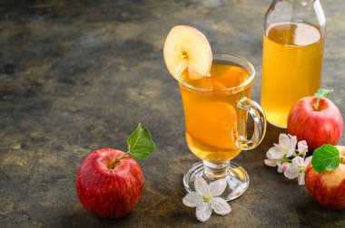 Ev yapımı mayalanmış kombu çayı ya da koyu kırsal bir zeminde bir dilim taze elmayla birlikte uzun bir bardakta elma şarabı..