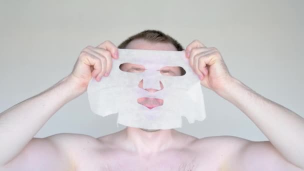 Caucasian man covers his face with a cosmetic mask. — Stock Video