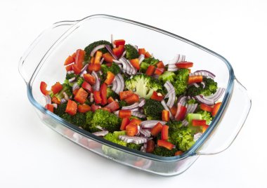 Beyaz zemin üzerinde bir cam tabakta sebze salatası