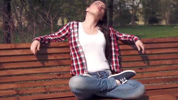 Adolescente assise sur un banc et léchant des bonbons — Video