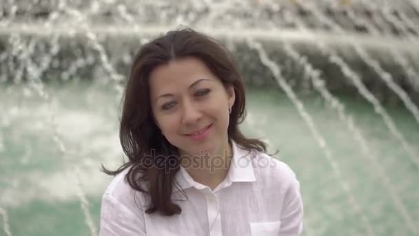 Szökőkút közelében egy gyönyörű fiatal nő portréja — Stock videók