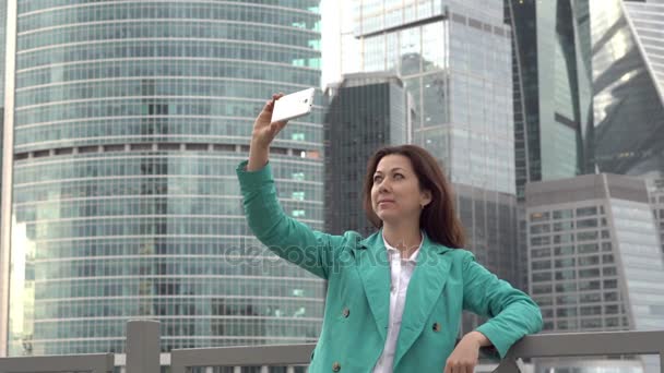 Stylish woman taking a selfie at buildings on bg — Stock Video