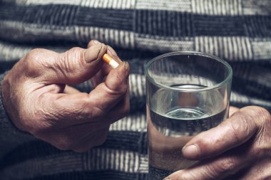 Yaşlıların elinde bir sürü renkli hap var.