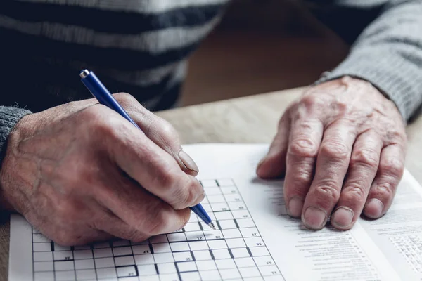 Senior resuelve sudoku o un rompecabezas de palabras cruzadas para ralentizar el progreso. — Foto de Stock