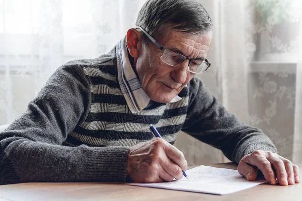 Senior resuelve sudoku o un rompecabezas de palabras cruzadas para ralentizar el progreso. —  Fotos de Stock