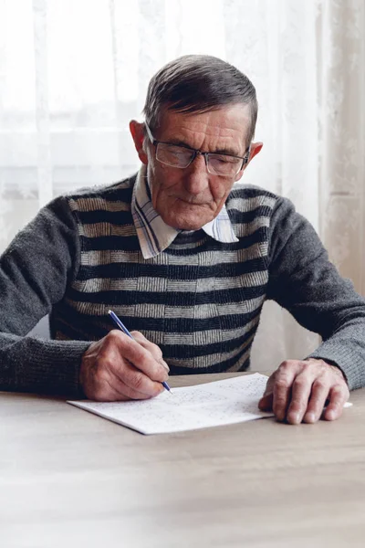 Senior löser sudoku eller ett korsord pussel för att bromsa progressi — Stockfoto