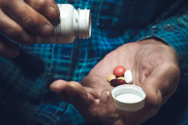 Many multi-colored pills in a Seniors hands — Stock Photo, Image