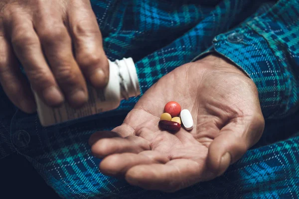 Viele bunte Pillen in der Hand eines Senioren — Stockfoto