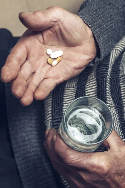Un anziano prende pillole con un bicchiere d'acqua — Foto Stock
