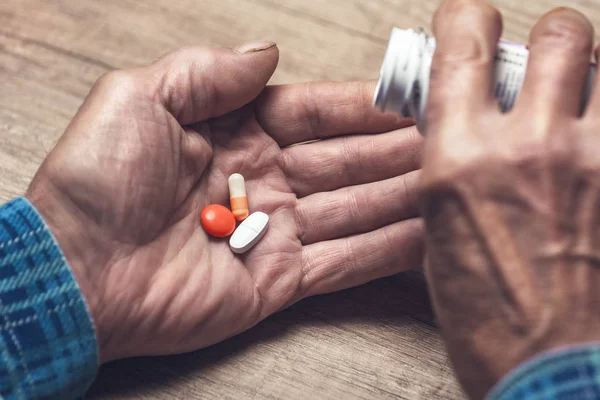 Viele bunte Pillen in der Hand eines Senioren — Stockfoto