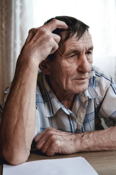 Senioren zitten aan tafel en denken aan iets of forg — Stockfoto