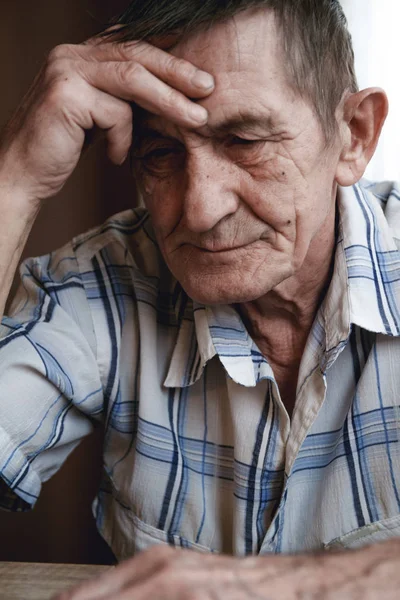 Senior sitter vid bordet och tänker på något eller forg — Stockfoto