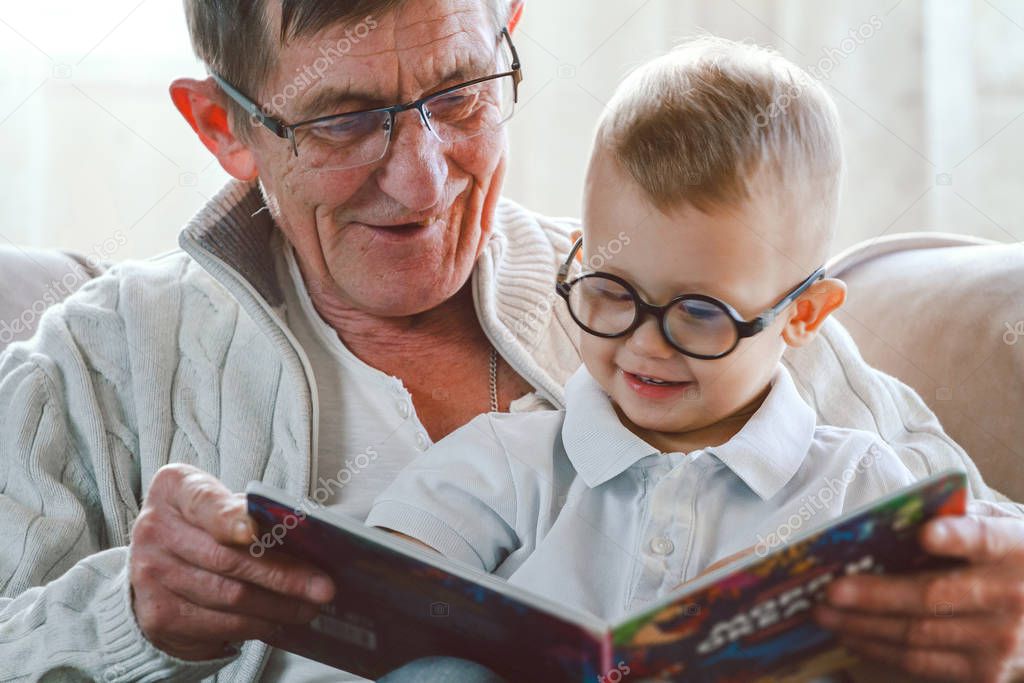 Grandfather and grandson are reading a book