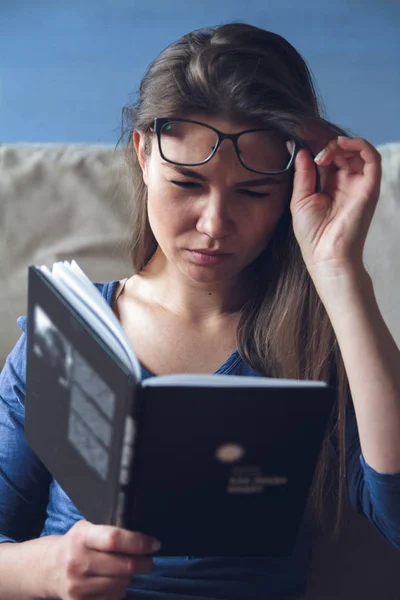 Görme sorunu olan bir kadın gözlüklü bir kitap okuyor.. — Stok fotoğraf