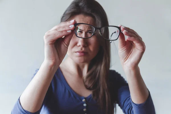 Egy látászavaros nő szemüveget tart. — Stock Fotó