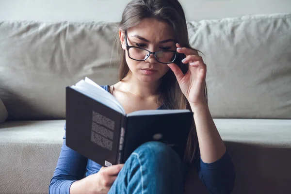 Una mujer con problemas de visión está leyendo un libro con gafas . — Foto de Stock