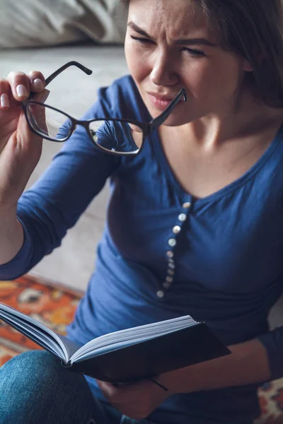 Görme sorunu olan bir kadın gözlüklü bir kitap okuyor.. — Stok fotoğraf