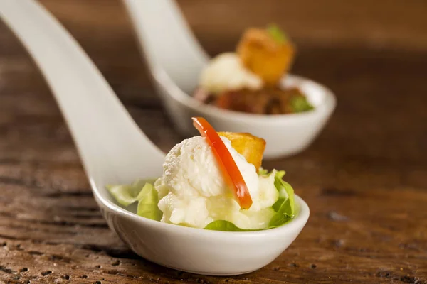 Baby lettuce salad, cherry tomatoes, palm hearts, cauliflower sauce, fried manioc and salted whipped cream in a spoon — Stock Photo, Image