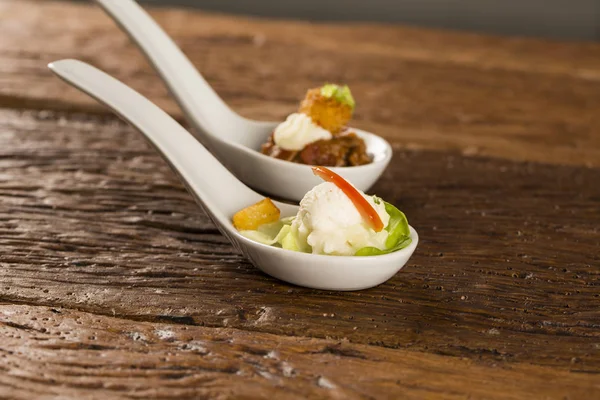 Baby lettuce salad, cherry tomatoes, palm hearts, cauliflower sauce, fried manioc and salted whipped cream in a spoon. — Stock Photo, Image