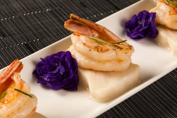 Gegrilde garnalen met rauwe nagel vis op witte plaat aan tafel — Stockfoto