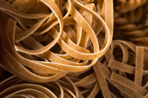 Vista superior de la pasta integral sin cocer sobre un fondo de madera —  Fotos de Stock