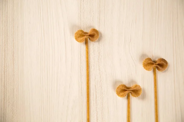 Целая интегральная макароны с цветами на белом деревянном столе — стоковое фото