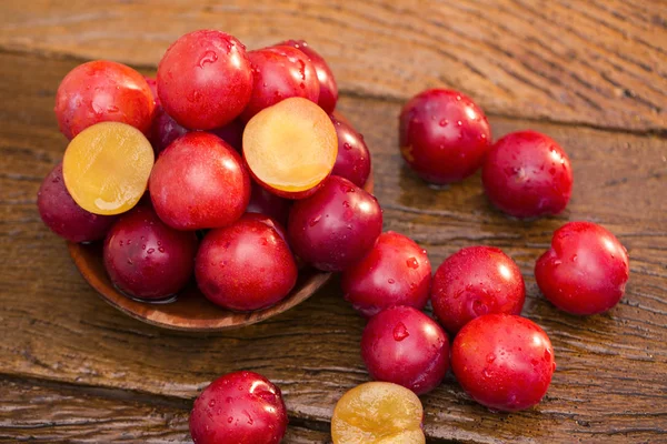 Prunes fraîches et brillantes sur fond en bois — Photo