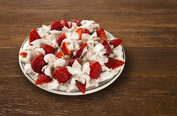 Φράουλα με κρέμα σαντιγύ σε ένα πιάτο σε ένα ξύλινο τραπέζι — Φωτογραφία Αρχείου