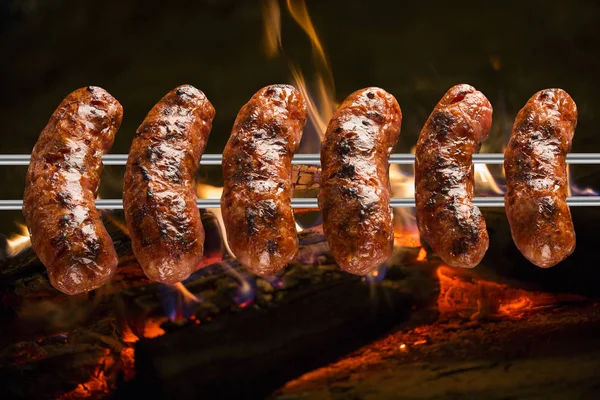 Korv på grillen spotta med flames — Stockfoto