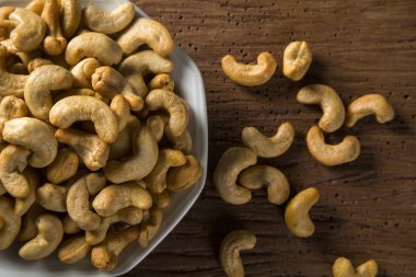 Kaju fıstığı ahşap arka plan üzerinde beyaz kase