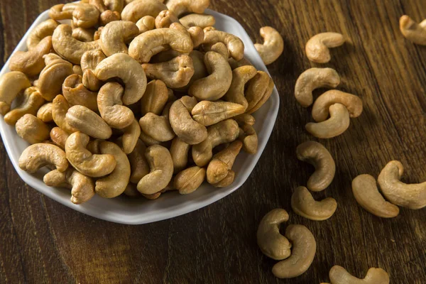 Cashew nuts in white bowl on wood background — Stock Photo, Image