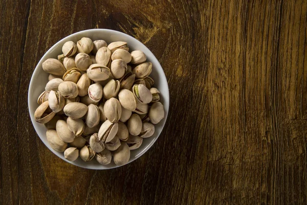 ahşap arka plan beyaz kase fıstık fındık.