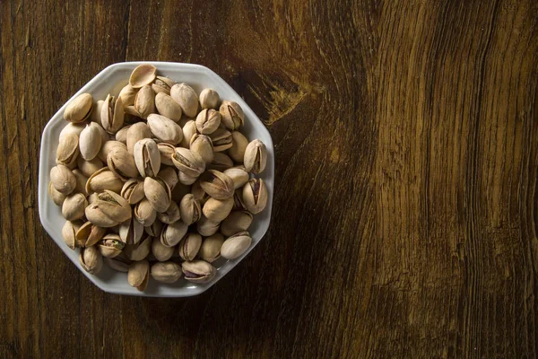 ahşap arka plan beyaz kase fıstık fındık.